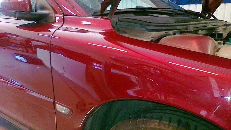 Reparerad buckla på röd volvo där bilen står i en BSC verkstad